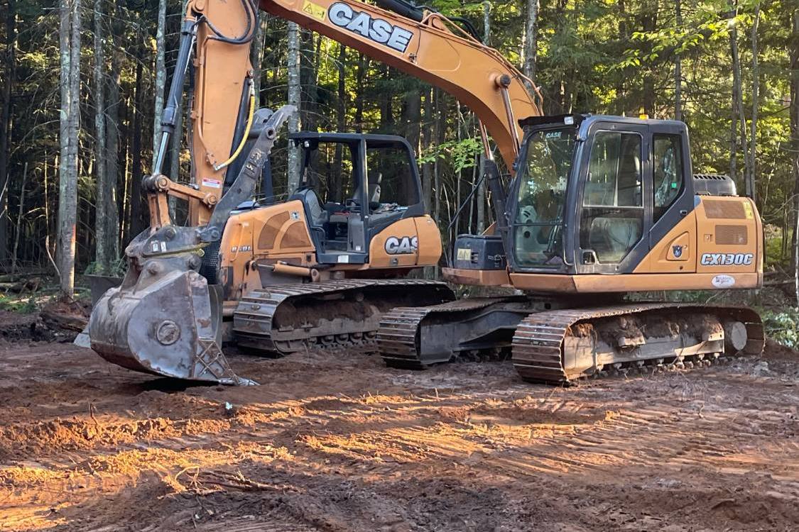 Case excavator and Case dozer side by side on a freshly cleared lot in late light