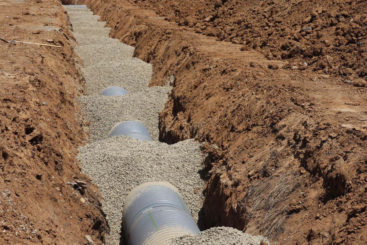 Perforated drainfield pipe bedded in washed stone in an open trench