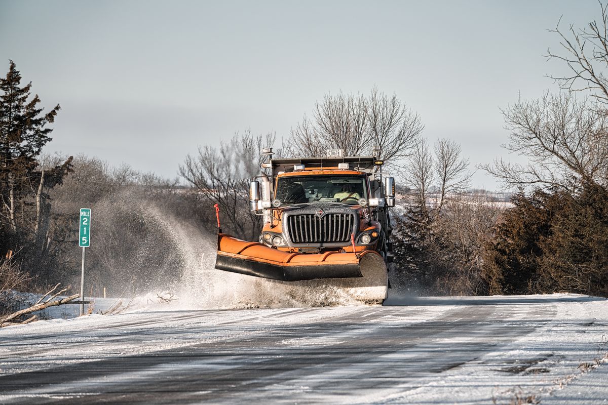 Plow truck clearing blowing snow from a rural road in winter