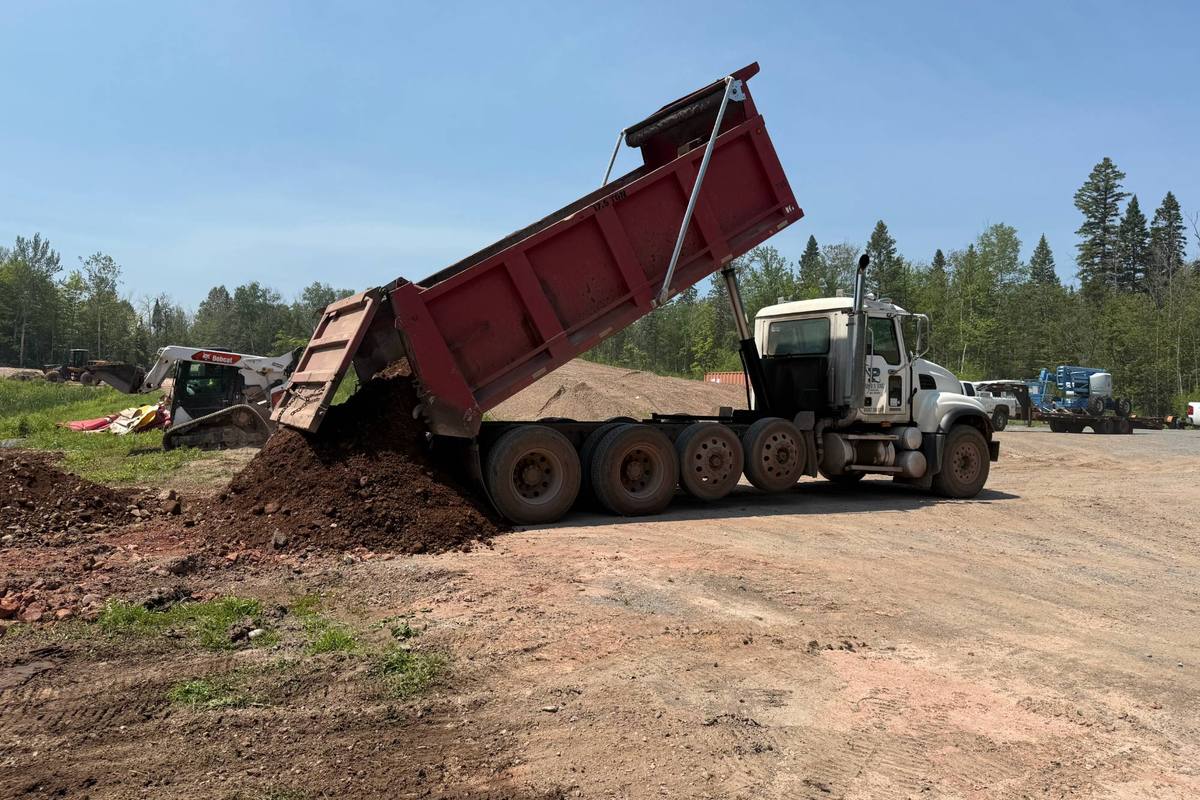 Parker and Sons dump truck tipping a load of topsoil on a job site